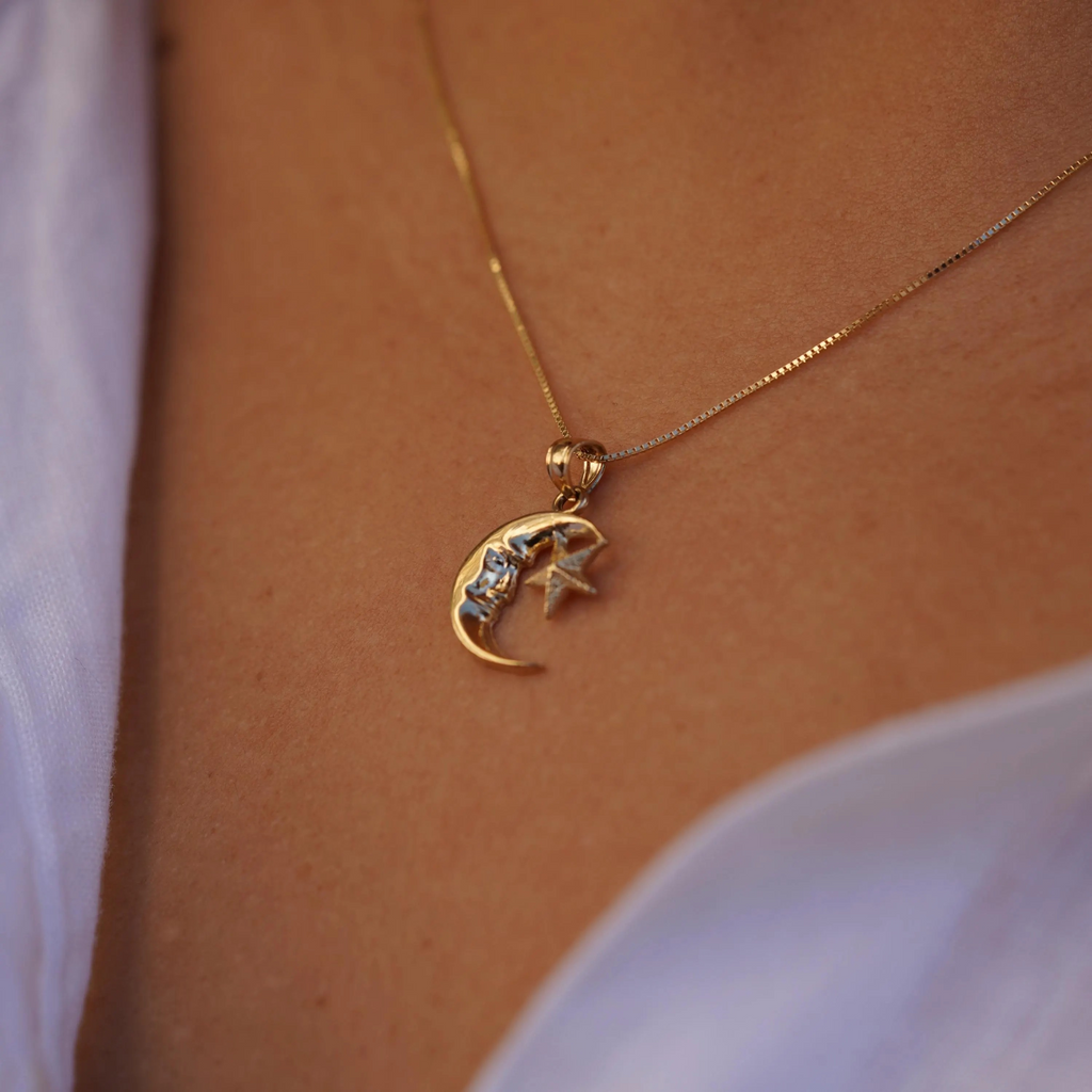 Angled view of a model wearing the 14K Gold Moon & Star Pendant, emphasizing its intricate celestial design and radiant yellow gold finish.