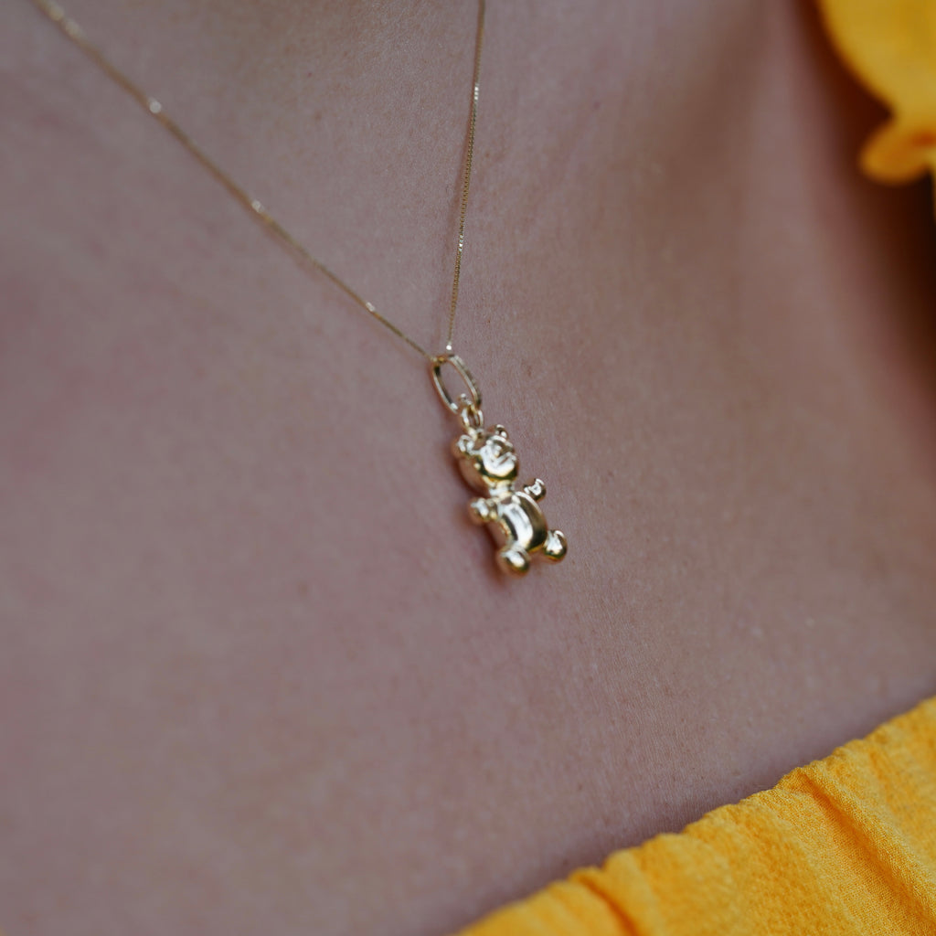 Side angle of a model wearing the 14K Real Gold Bear Pendant on a chain, highlighting the charm's unique craftsmanship and gold shine.