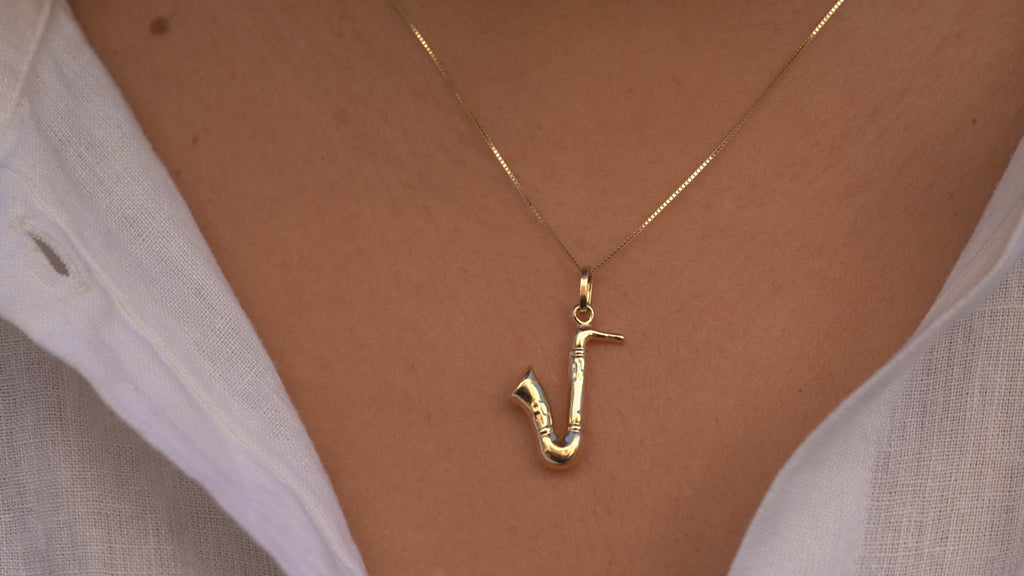 Video of a model wearing the 14K Gold Saxophone Charm, highlighting its detailed saxophone shape, radiant gold finish, and elegant movement on a chain.